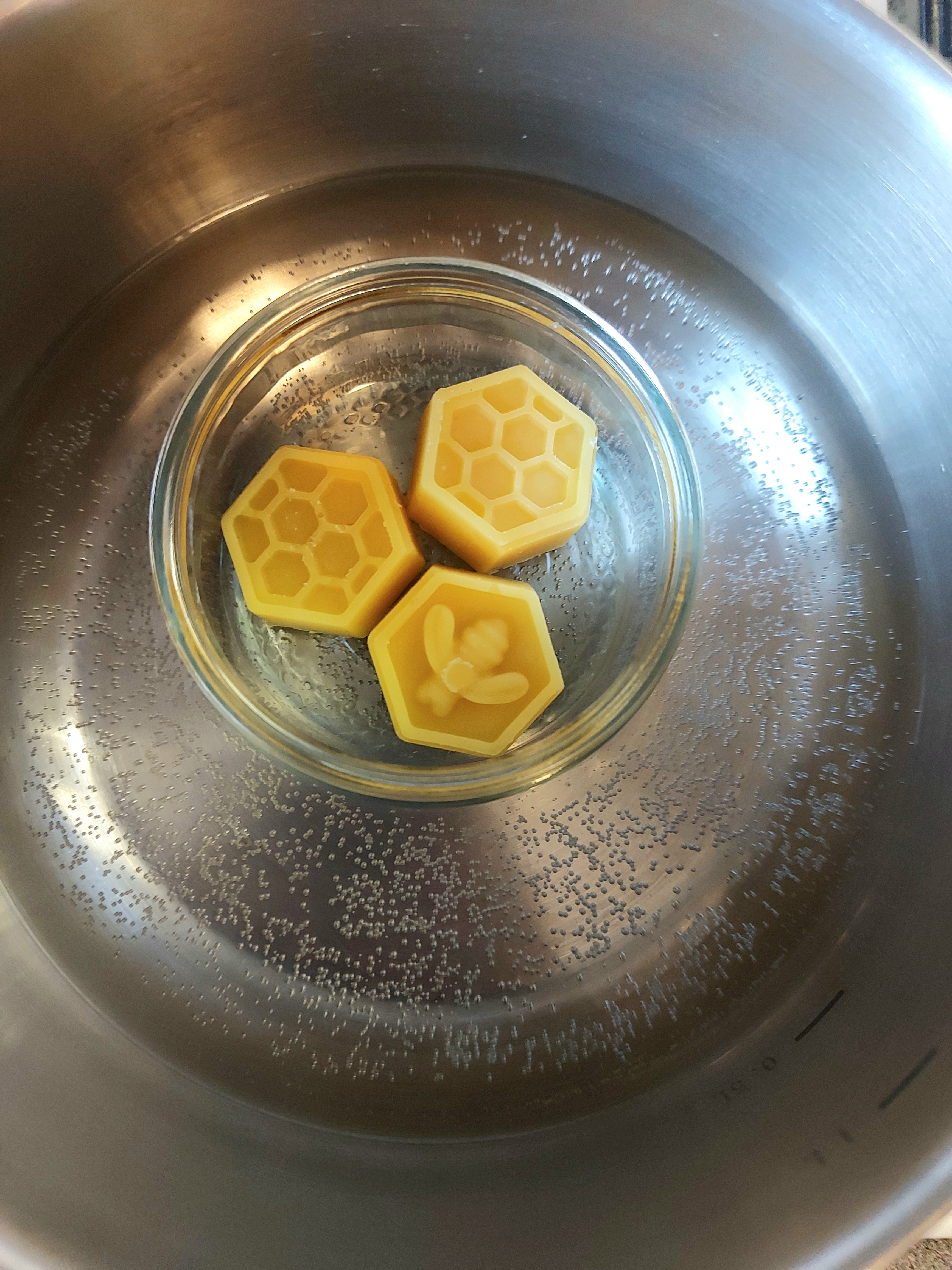 three beeswax blocks in a glass ramekin inside a pot of wimmering water