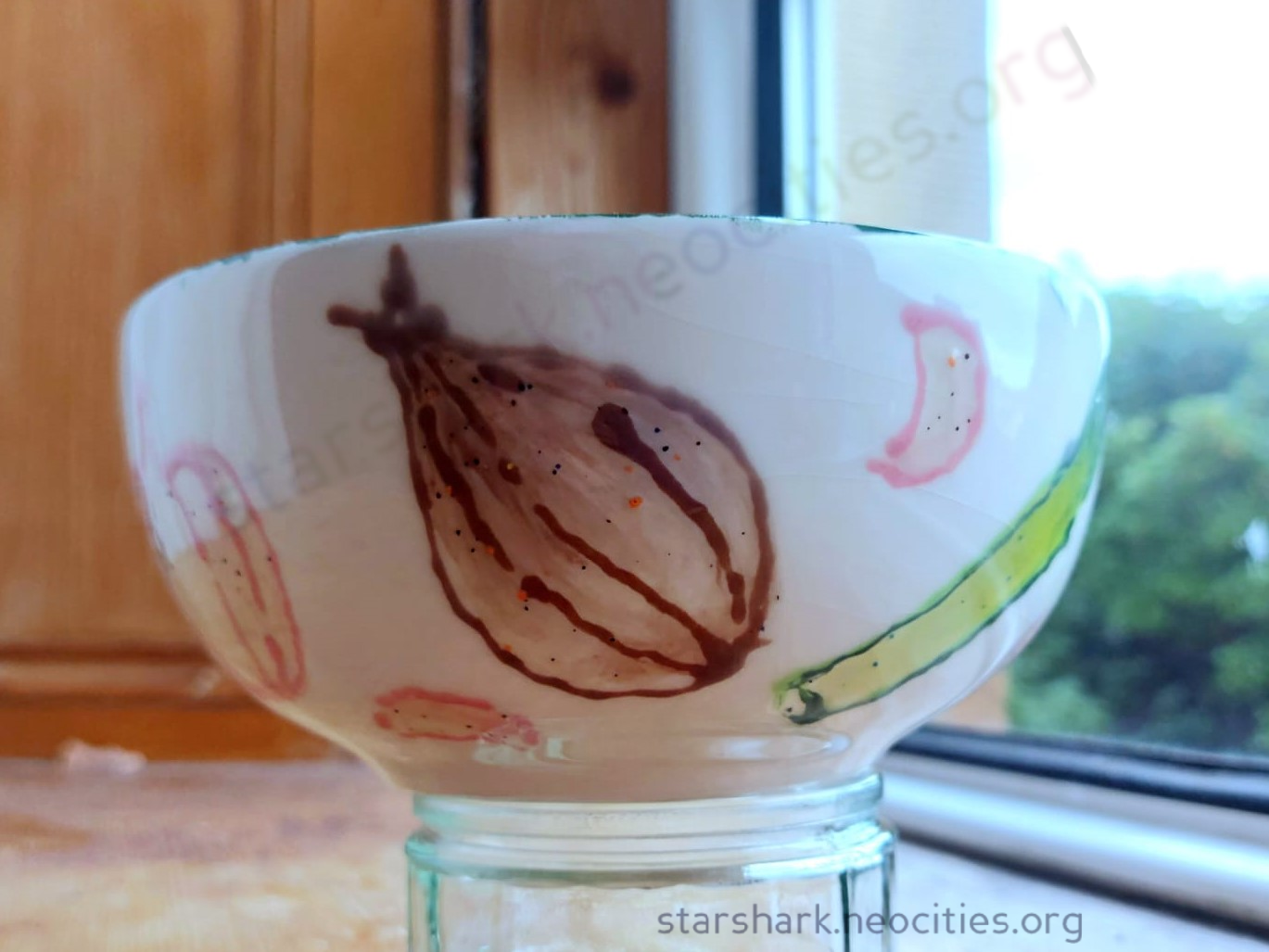a ceramic cereal bowl painted with varius alliums: a shallot, leek, and garlic gloves are viible.