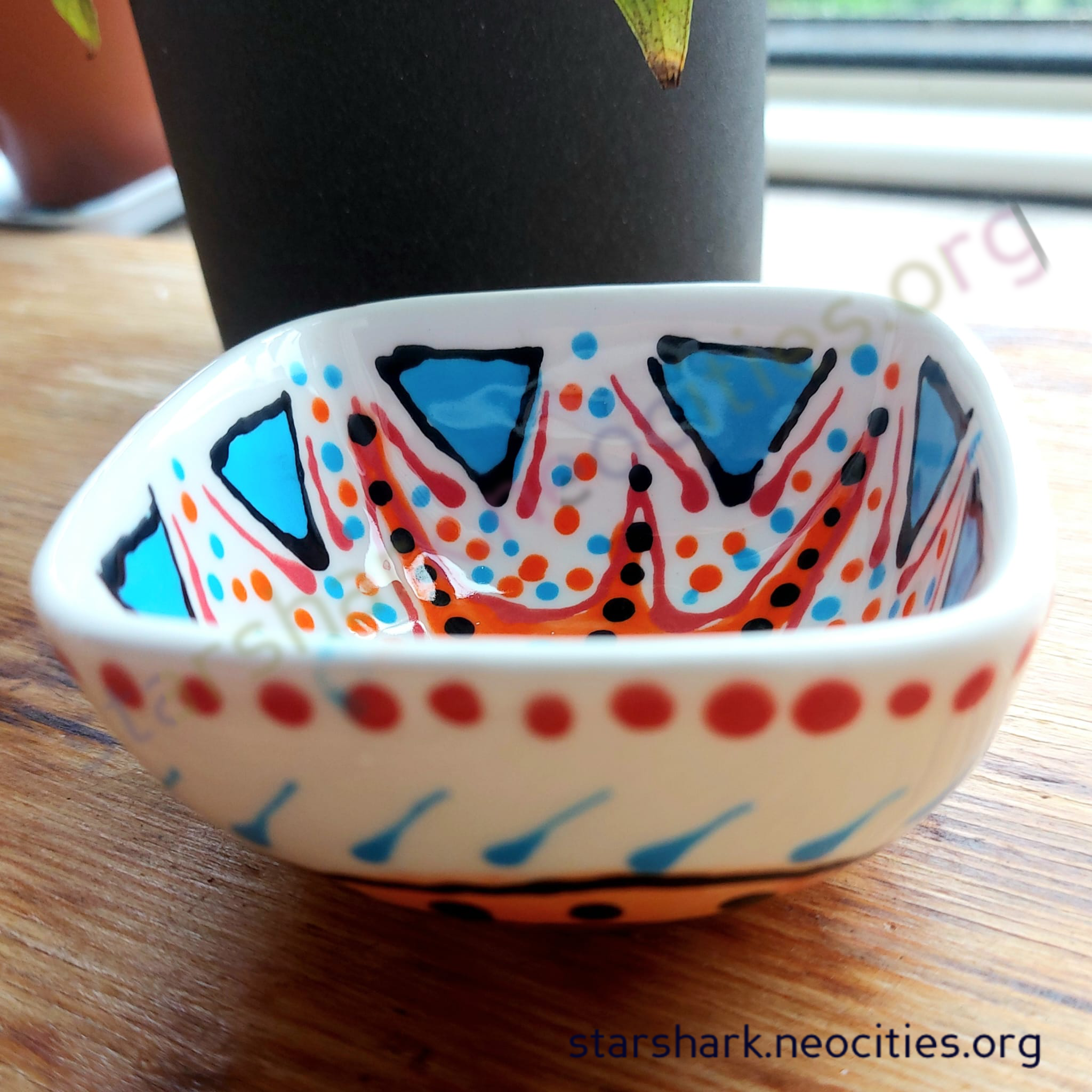 the first small ceramic trinket bowl with blue, orange, red and black designs.
