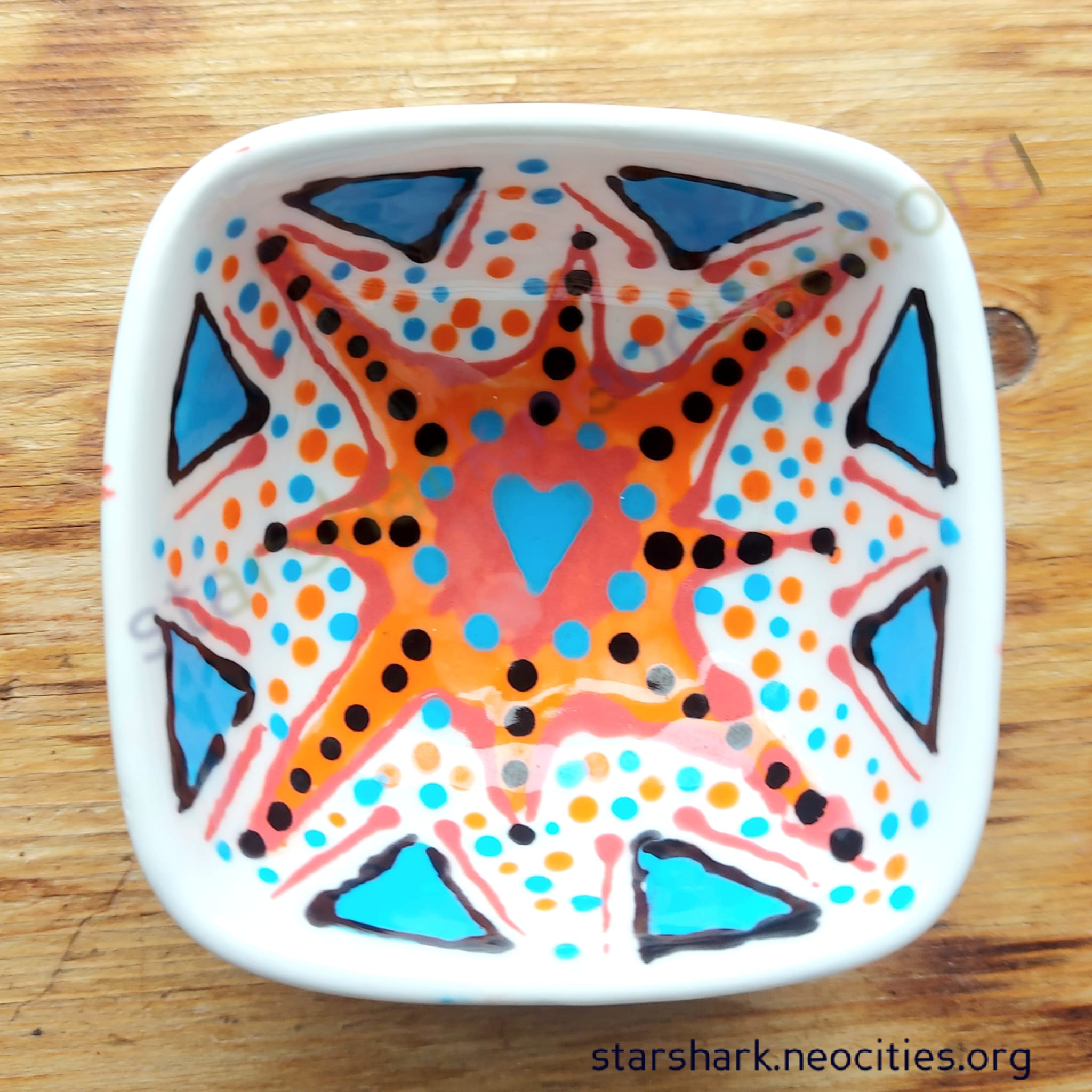 the first small ceramic trinket bowl with blue, orange, red and black designs.