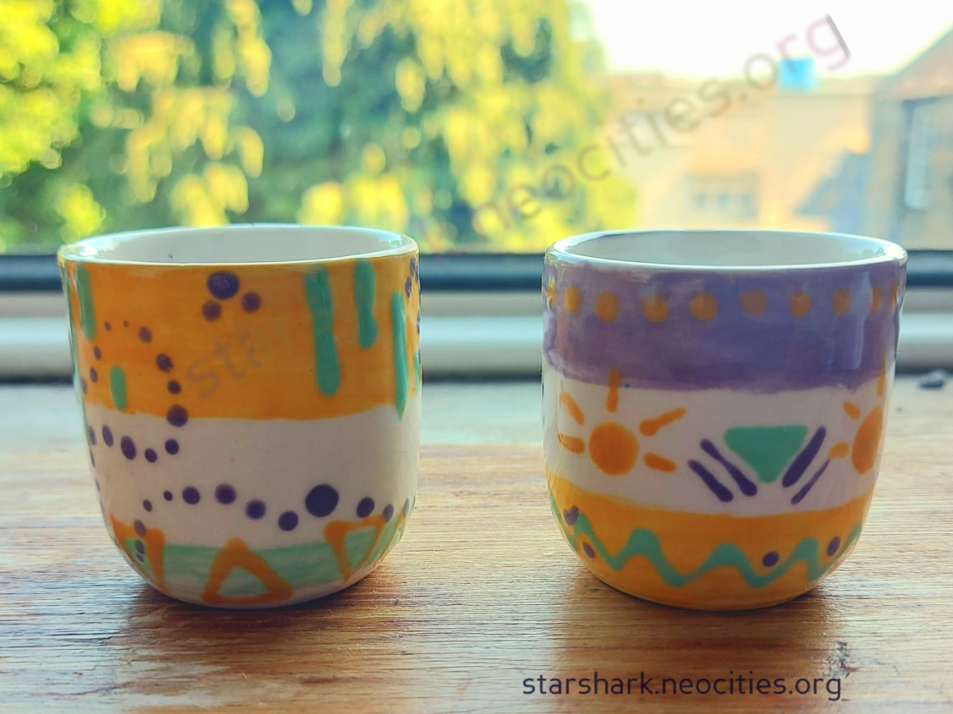 two ceramic espresso cups painted in yellow, green and pink.