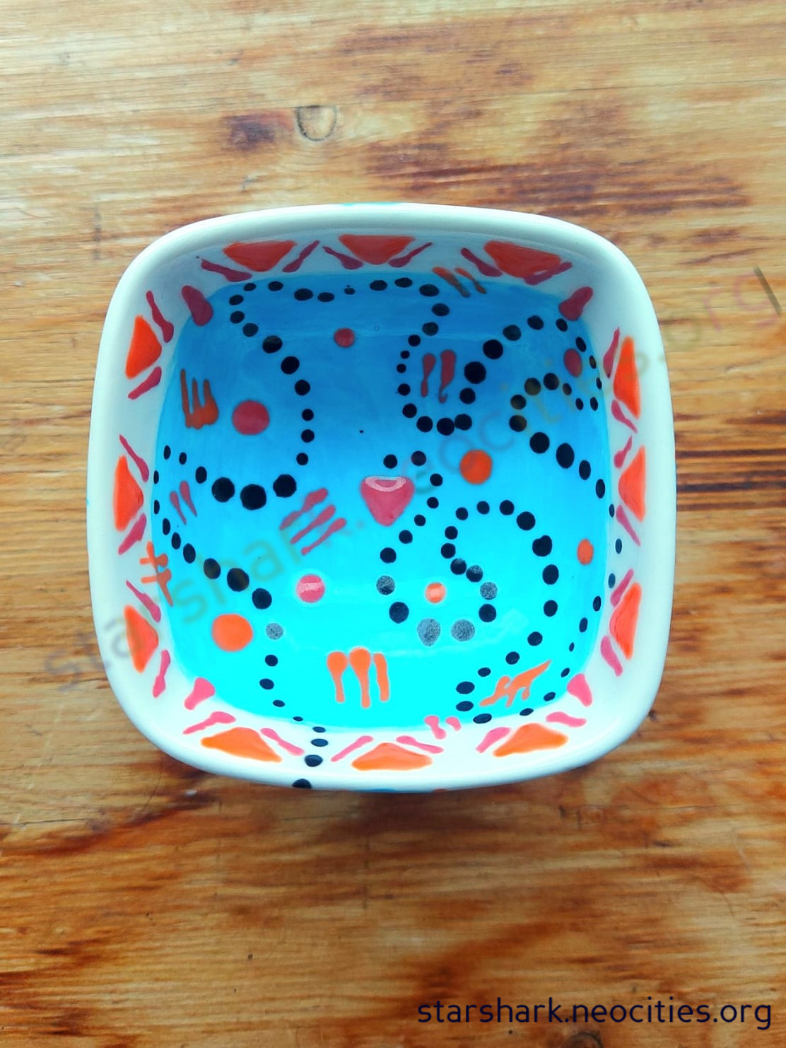 a second small ceramic trinket bowl with blue, orange, red and black designs.