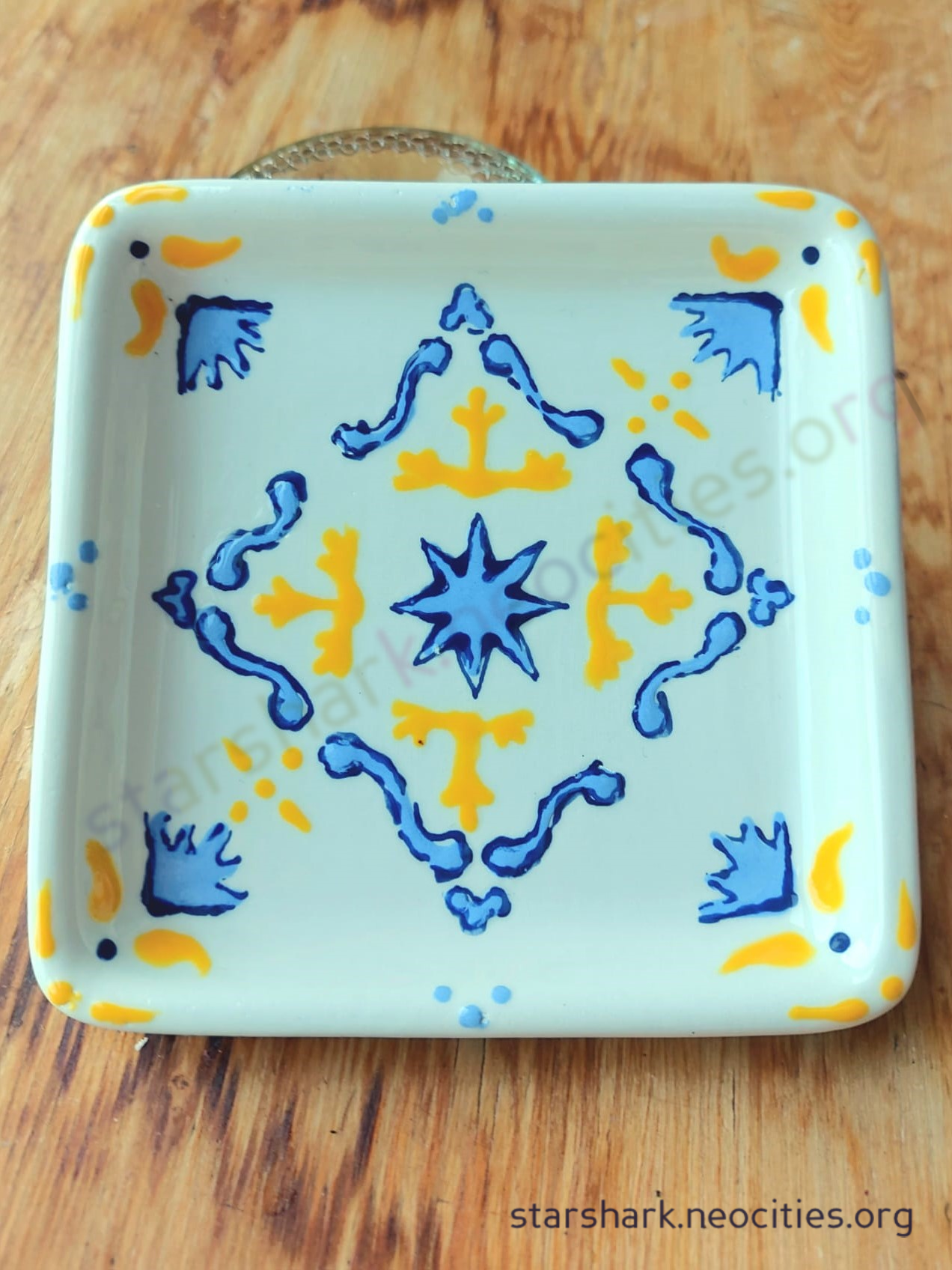 a square ceramic trinket dish with blue and yellow portugese tile-style designs